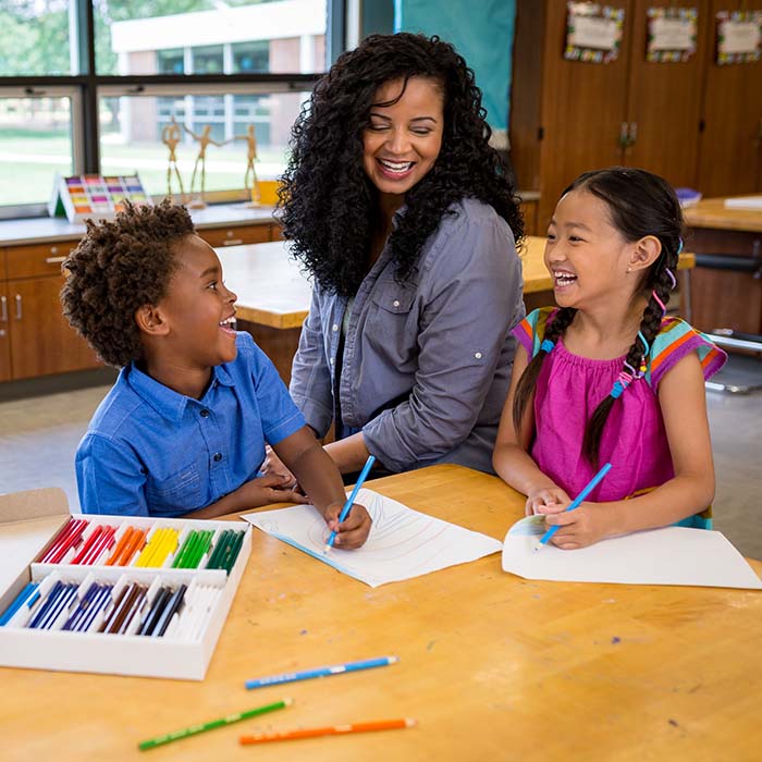 Young students laughing with their teacher.